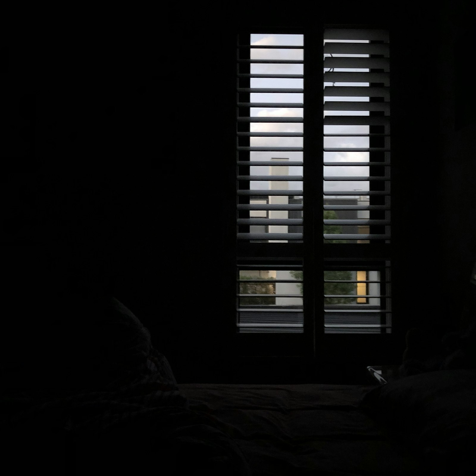 Donkere slaapkamer met blackout gordijnen die zonlicht buitenhoudt, symbool voor een koele en donkere slaapomgeving